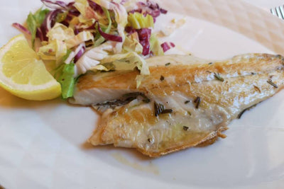 cooked branzino fillet with lettuce and lemon