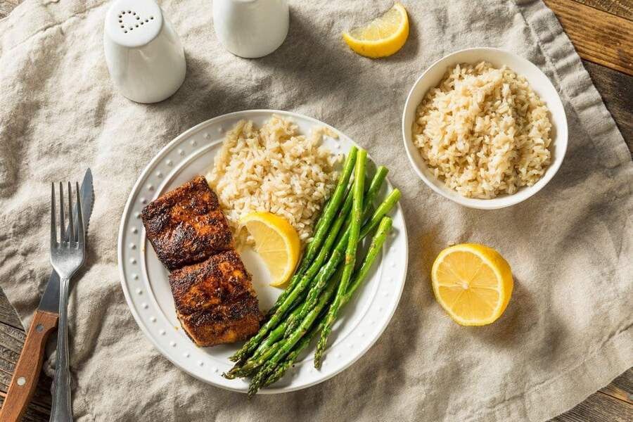 cooked mahi with rice and asparagus on a white plate