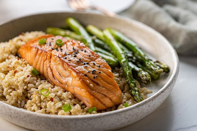 cooked norwegian salmon over a bed of rice with asparagus in a bowl