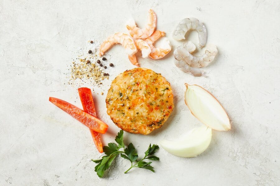 shrimp burger patty on a table with herbs