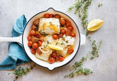 cooked wild alaska halibut in a pan with herbs and spices