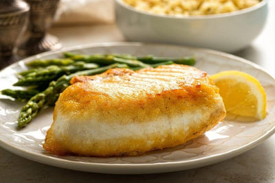 one cooked wild alaska halibut portion on a plate with asparagus