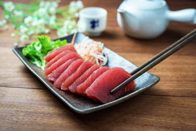 yellowfin tuna saku sushi with vegetables on a black plate