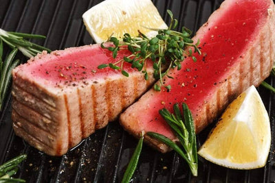 cooked yellowfin tuna steak with herbs and lemon in a pan