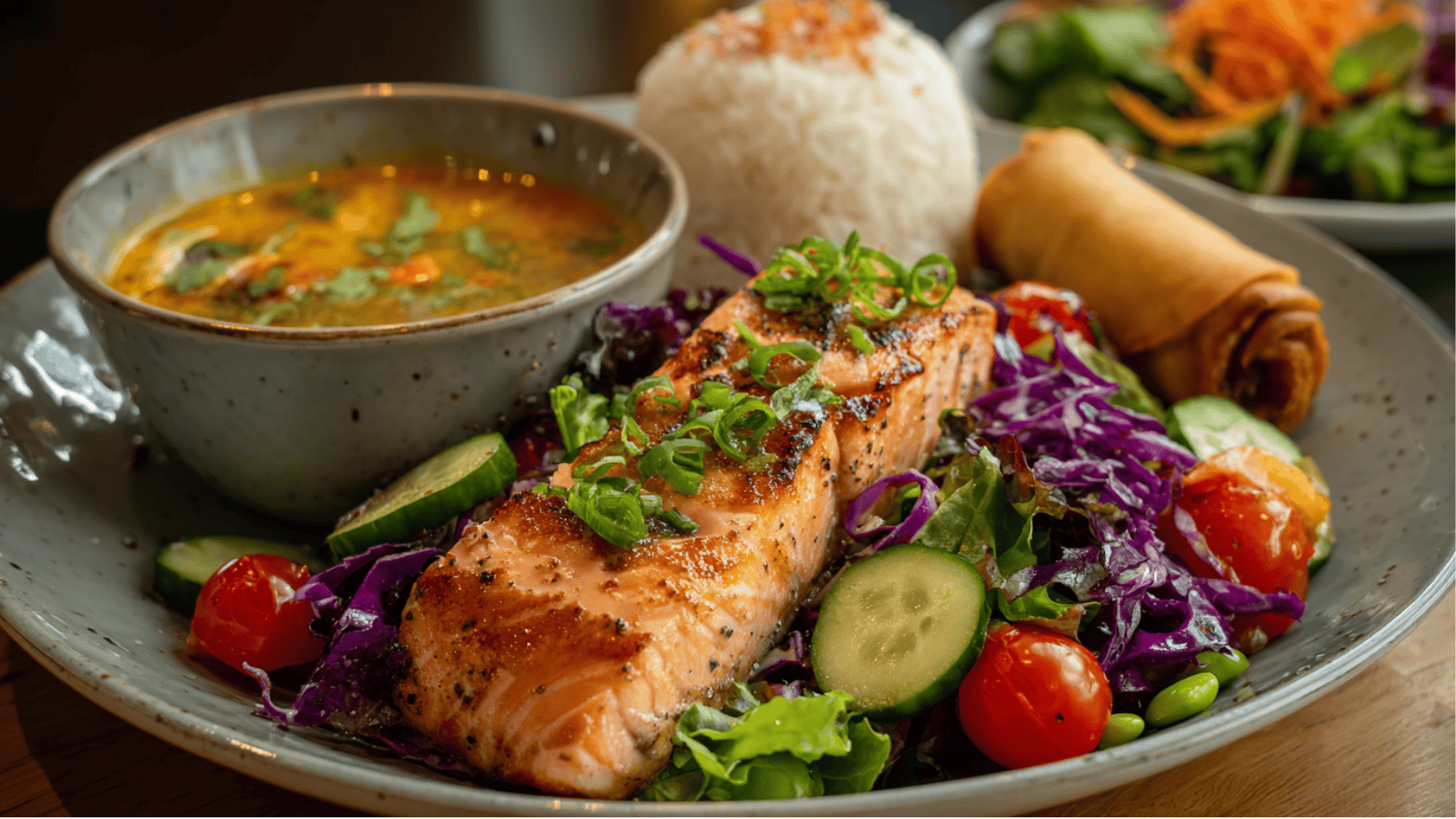 A plate featuring Thai-inspired salmon salad, accompanied by rice and a bowl of soup