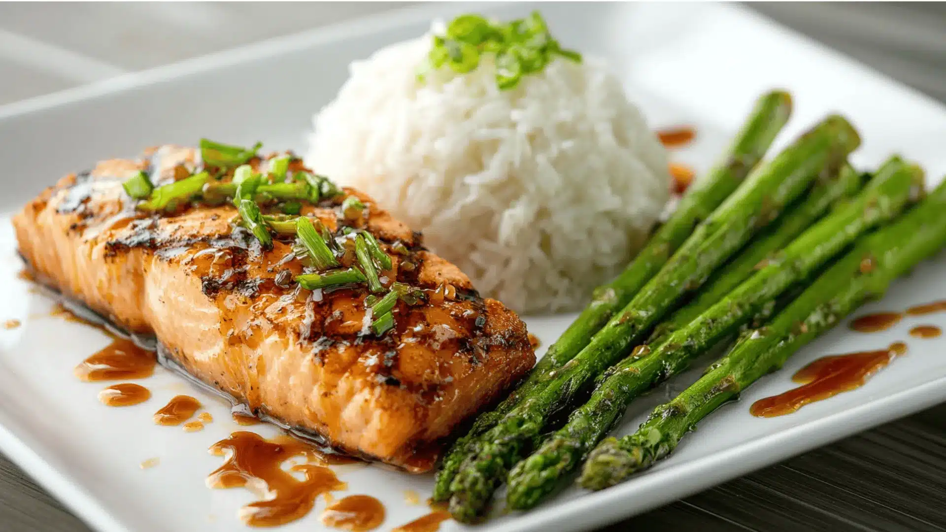 A plate featuring grilled salmon with maple ginger glaze, served alongside asparagus and rice