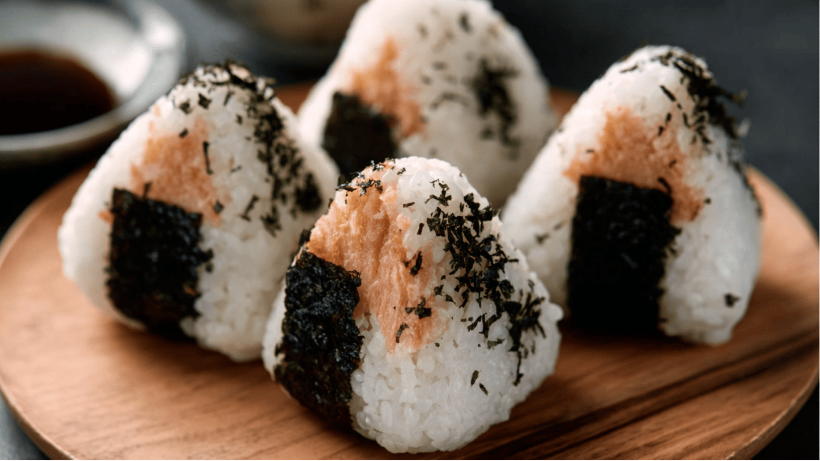 A sushi dish featuring a decorative layer of black and white stripes on top, served on a sleek plate