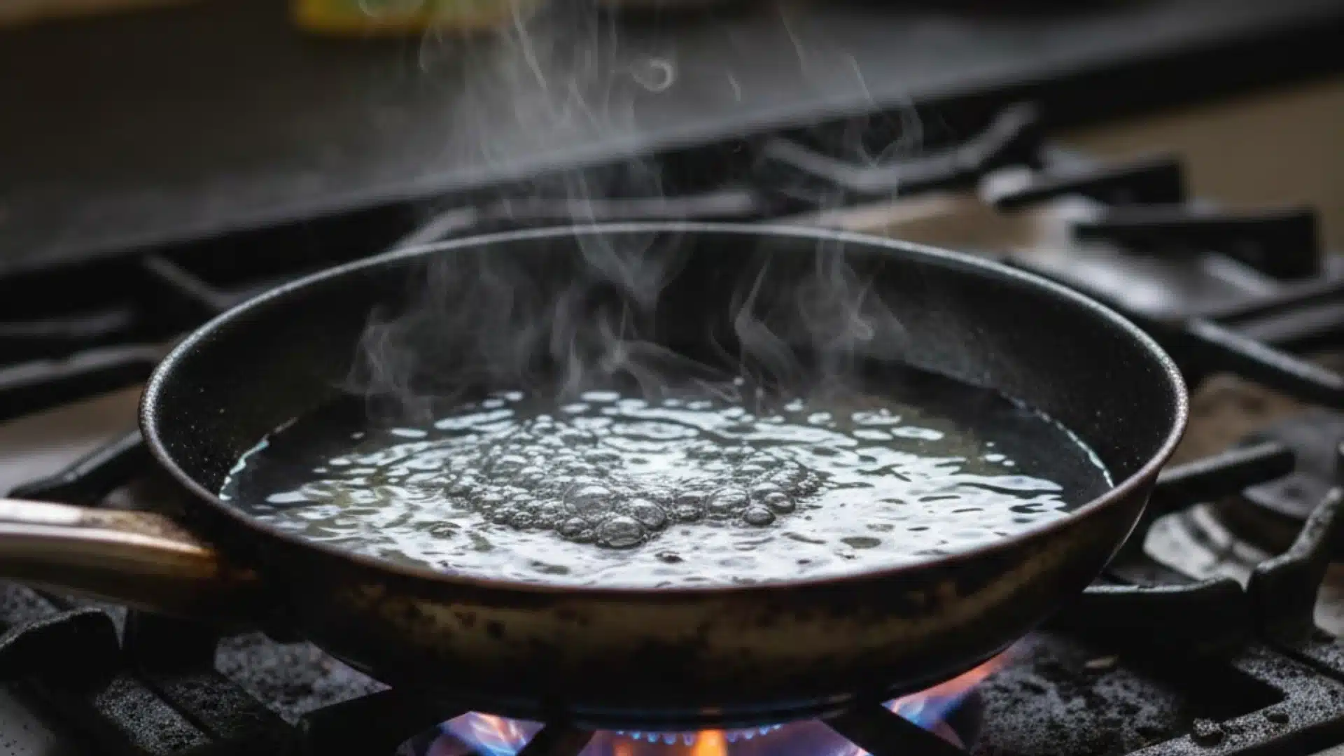 An image showing how to clean burnt pan with the deglazing method, with the burnt pan over a lit gas stove, and with water boiling