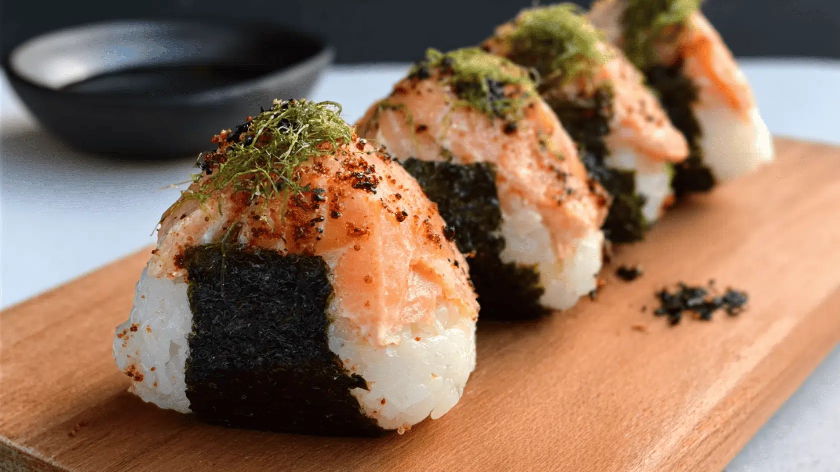 Sushi rolls with salmon and seaweed arranged on a wooden board, showcasing a traditional Japanese dish