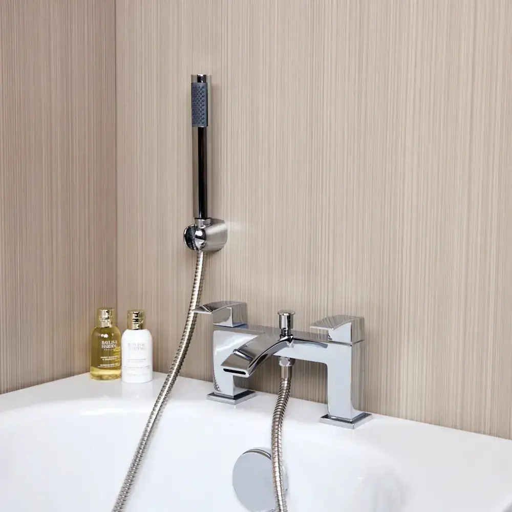 Chrome bathtub faucet with shower attachment and toiletries on white tub edge in modern bathroom