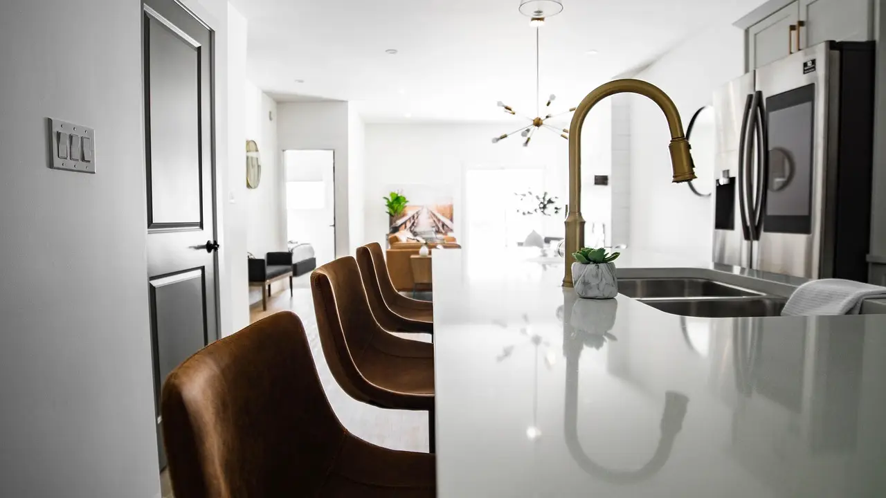 Modern kitchen with brown leather chairs, white island, and stainless steel appliances in bright light