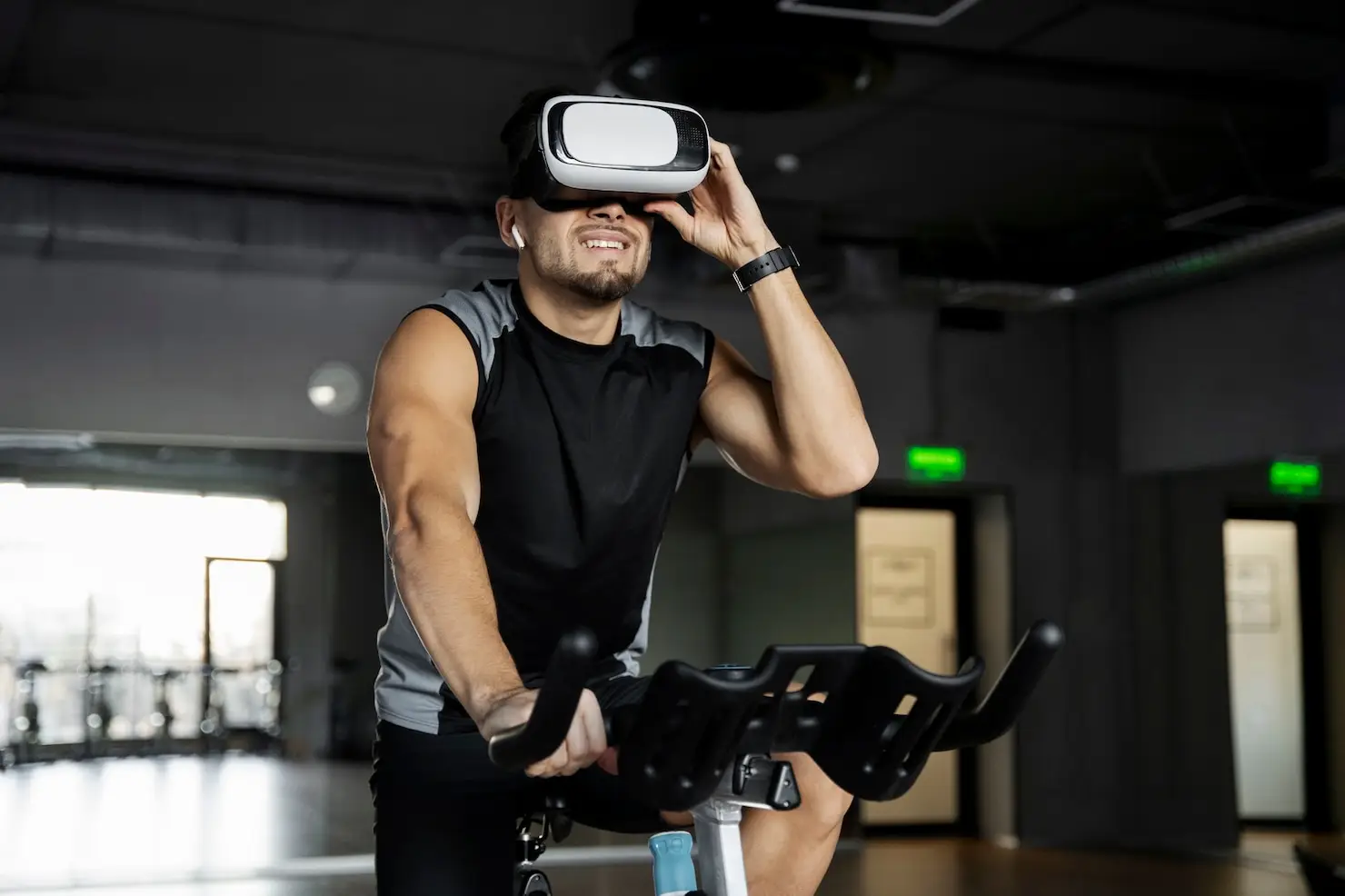 Man wearing VR headset cycling on exercise bike in a modern gym setting