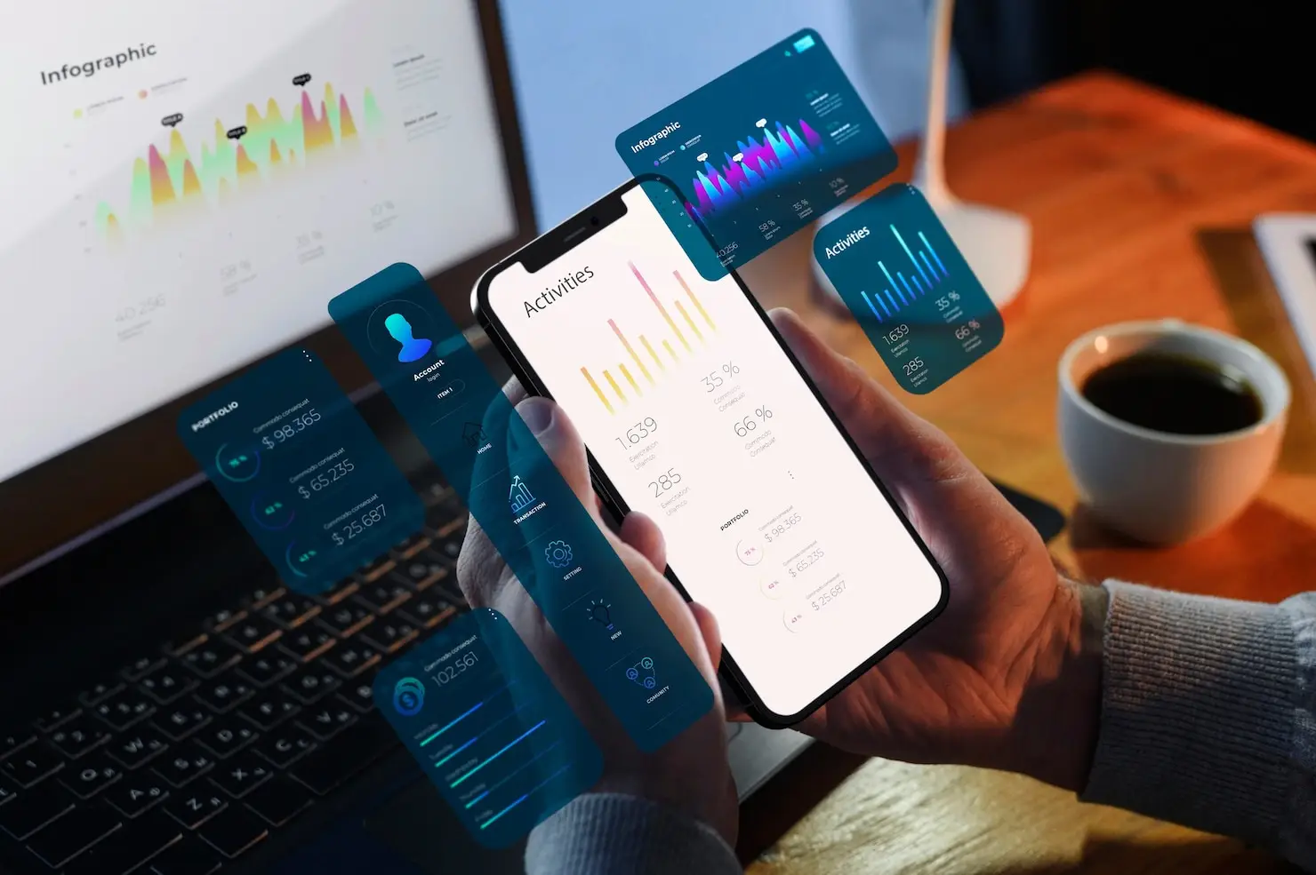 Person holding smartphone with data analytics apps near laptop and coffee on wooden desk
