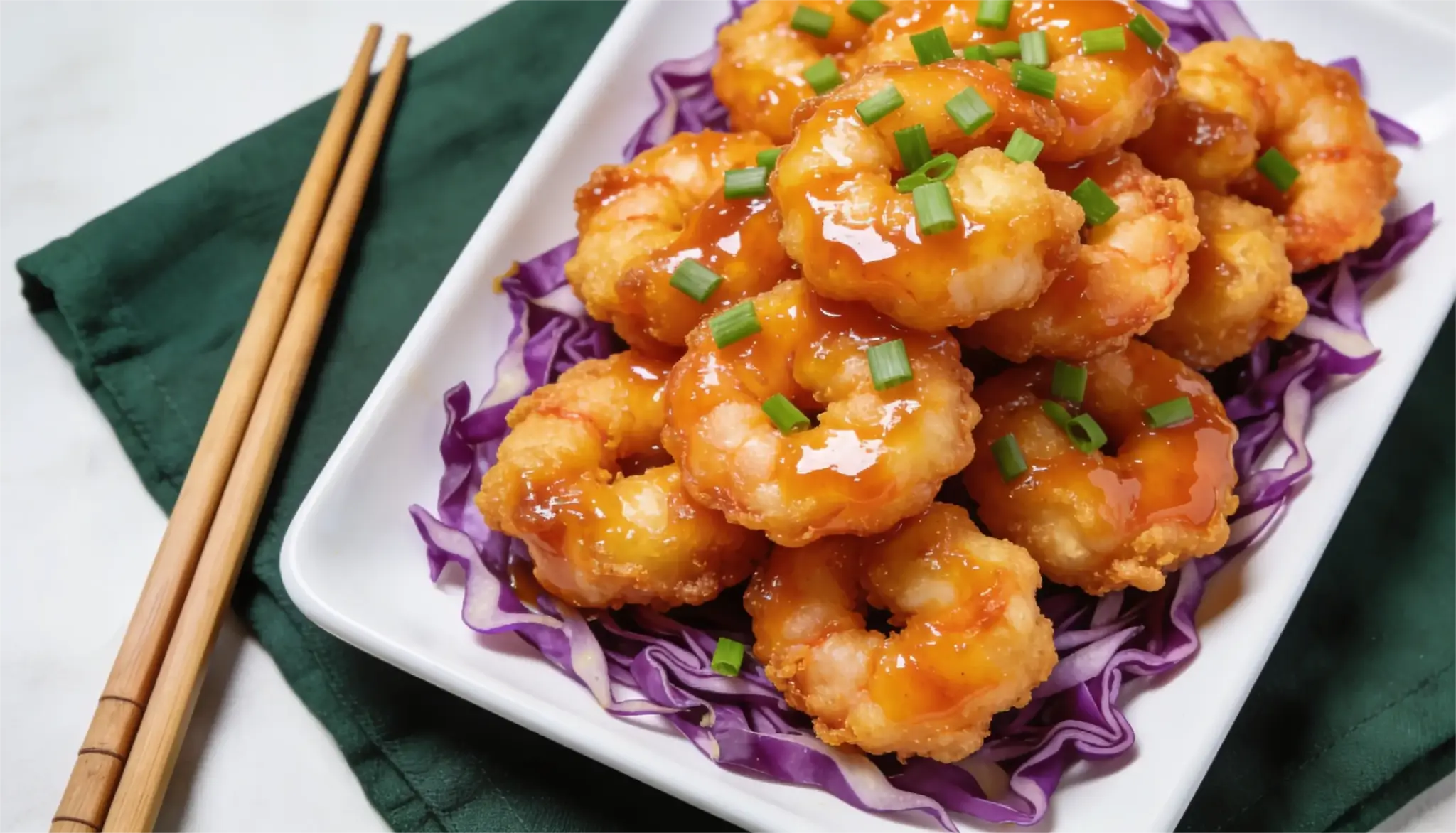 Crispy fried shrimp with orange sauce and green onions served over purple cabbage.