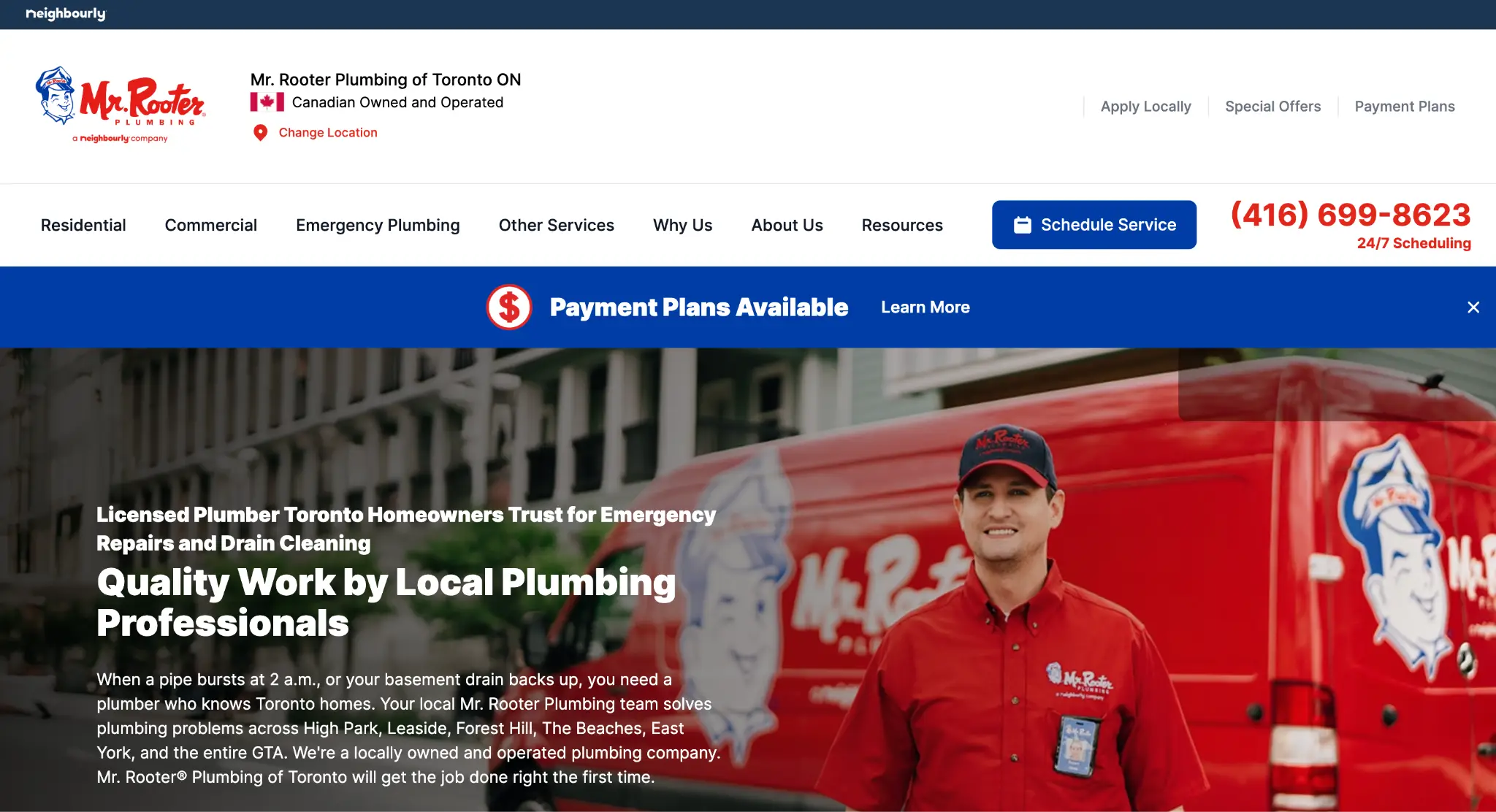 Smiling person in red uniform standing next to branded red plumbing van