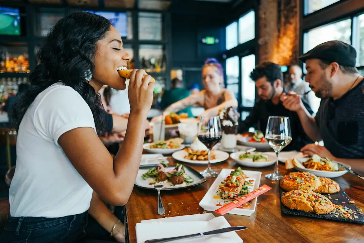 Group of people dining at a restaurant table with various dishes and drinks