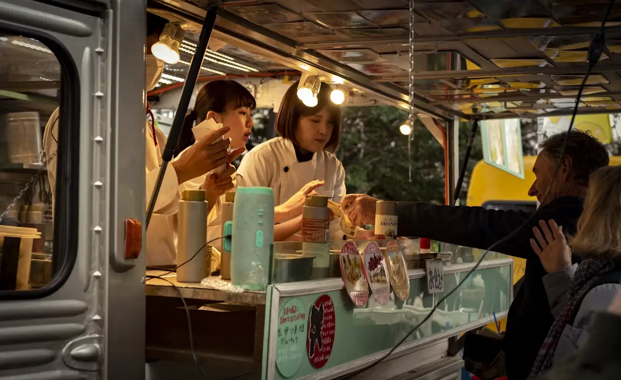 Street food vendors serving customers from a food truck under warm lights