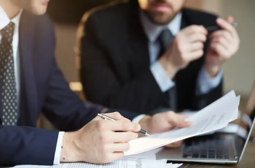 Business professionals reviewing documents at a desk with laptop in office setting