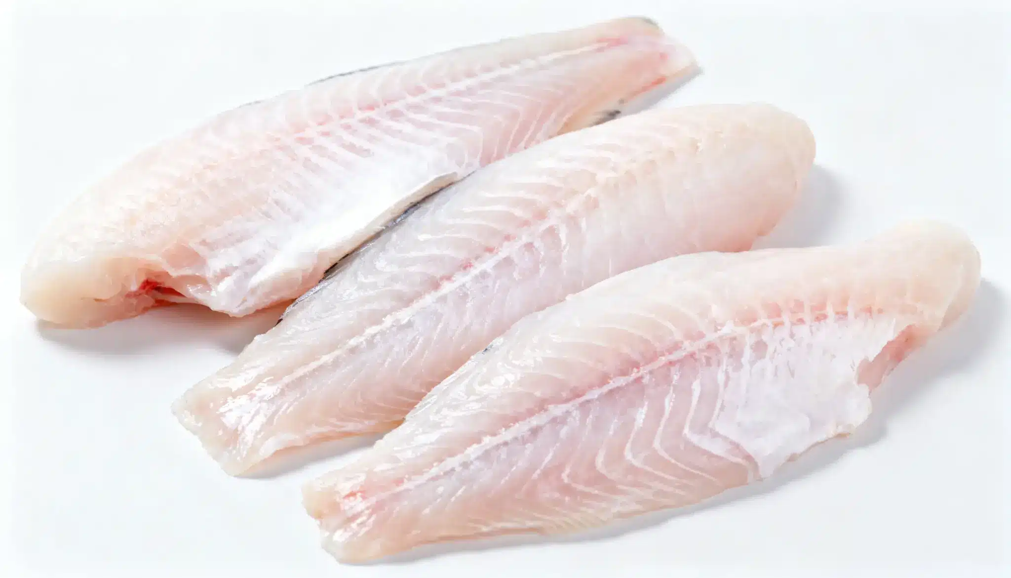 Three raw, white fish fillets arranged on a white background.