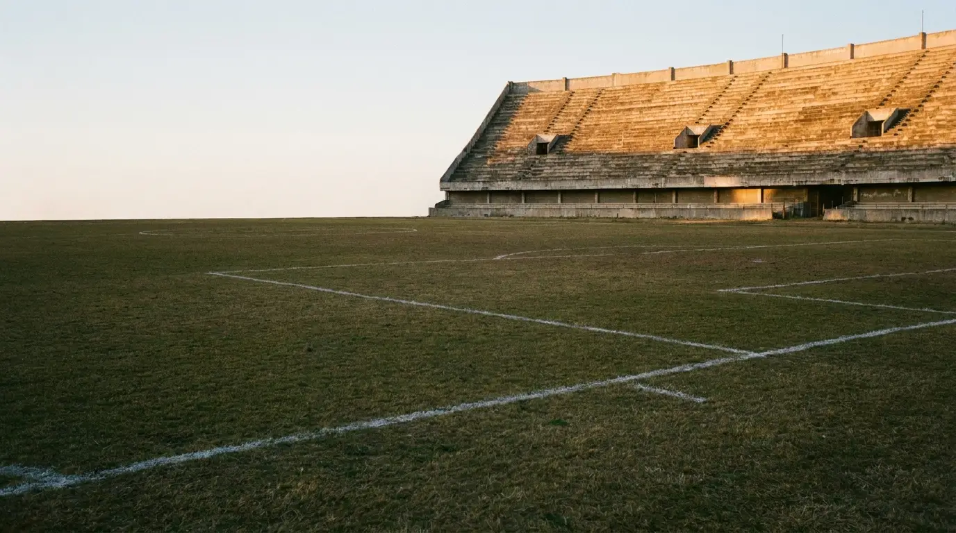 Bleachers in an empty sports stadium under warm sunlight on a grassy field