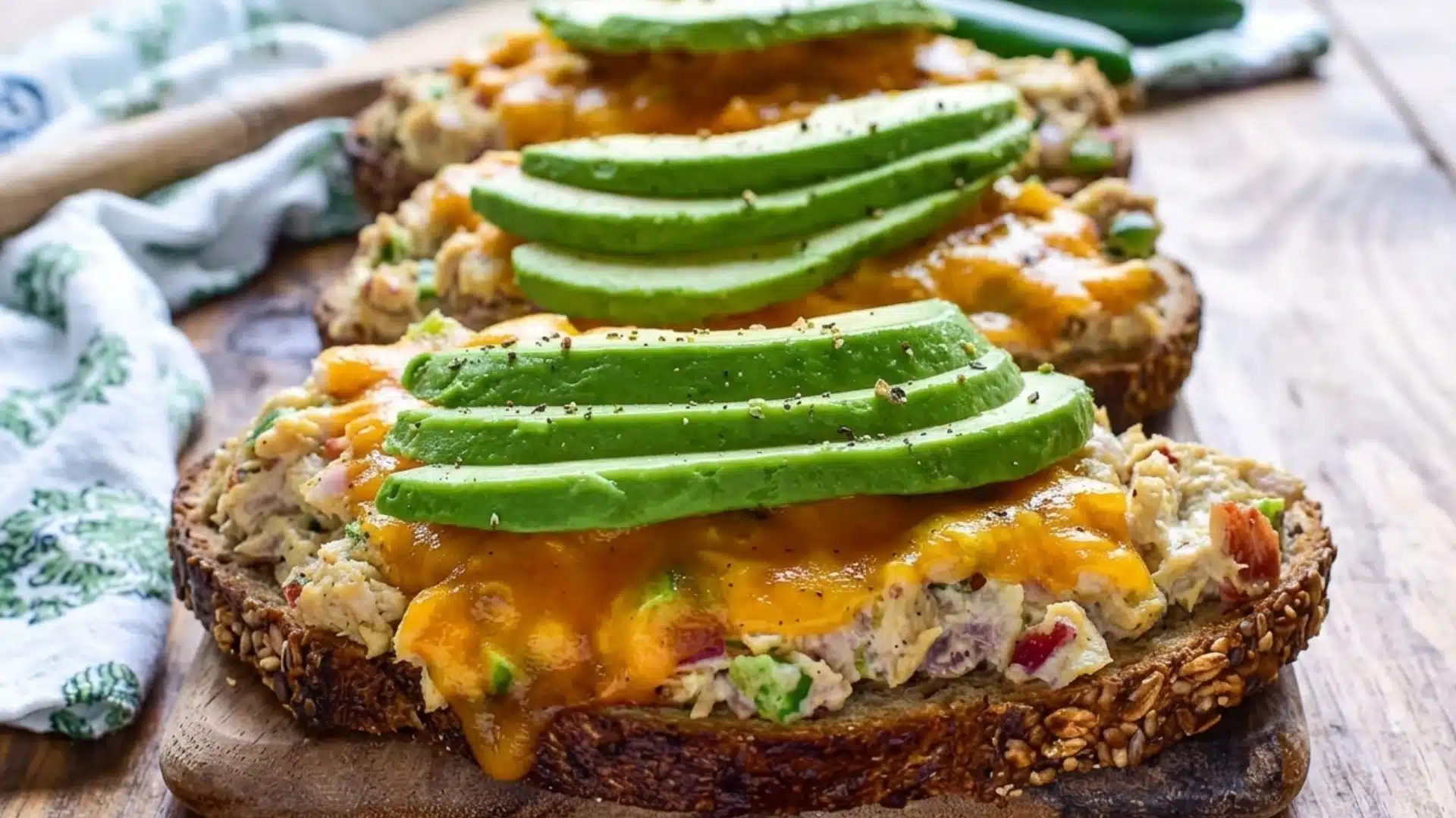 Seeded bread topped with melted cheddar and sliced avocado.