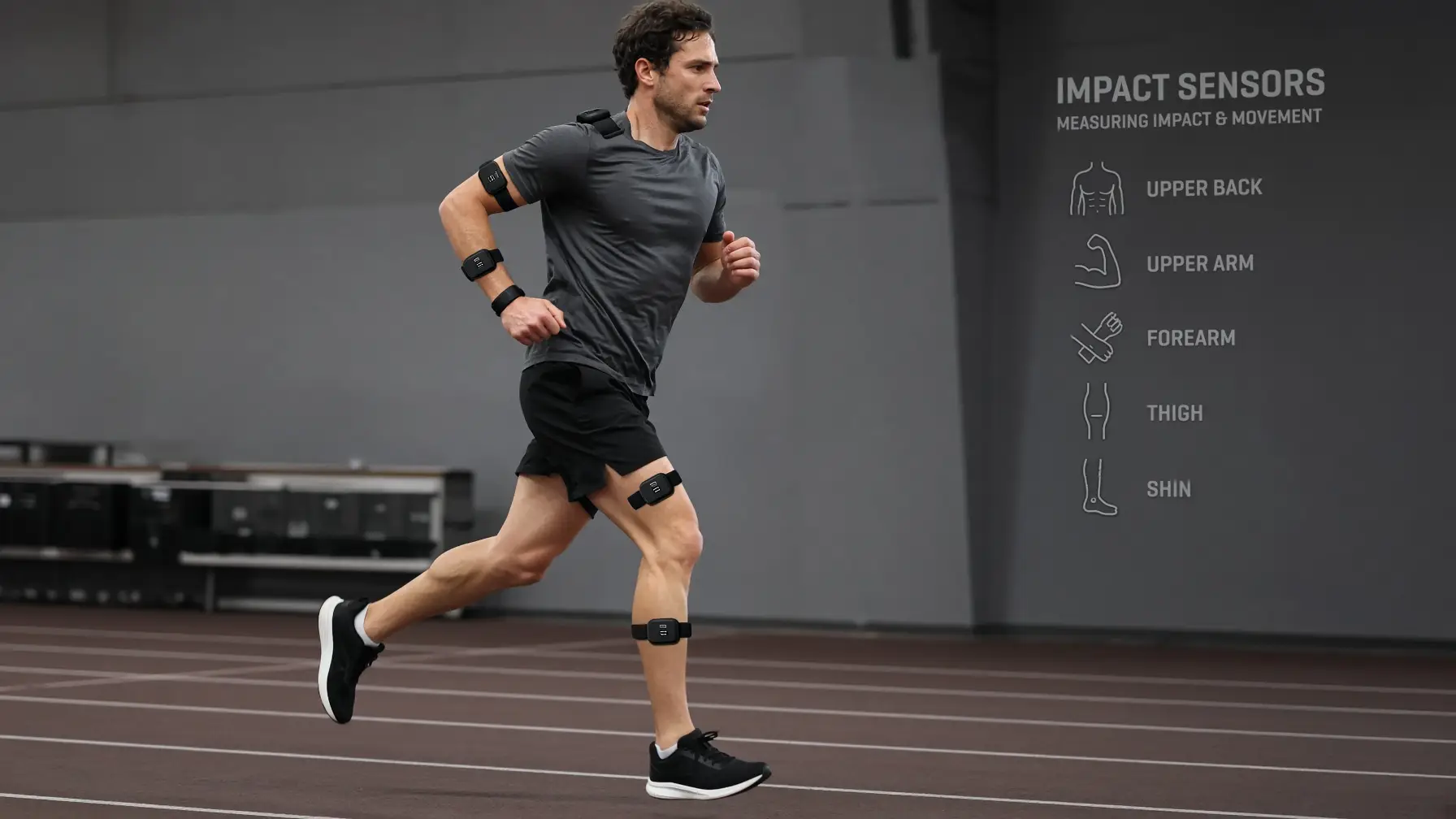 Man running on indoor track wearing impact sensors on upper arms and legs